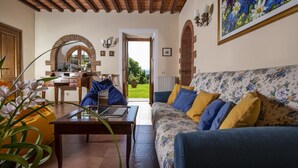 Un accogliente soggiorno con un divano, un tavolino da caffè e un portatile. Si apre una porta che dà sul giardino.