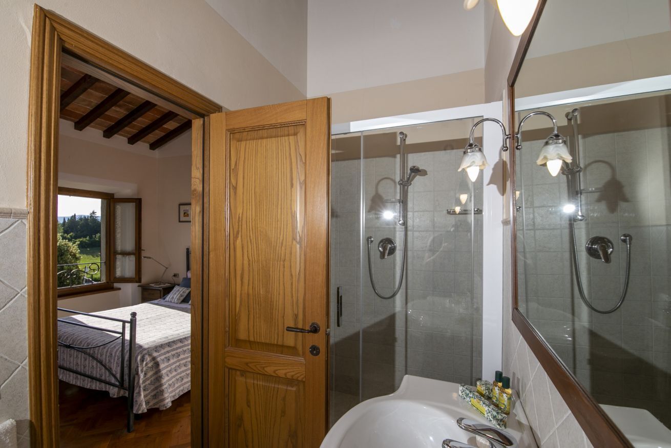 Een slaapkamer met een bed, een houten deur en uitzicht op de omgeving.