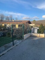Zona residencial con una casa de techo de tejas y jardín cercado.