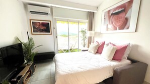 Hotelkamer met een bed, een televisie, een bureau en een balkon met uitzicht.