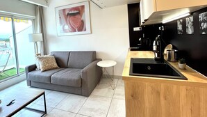 Een moderne keuken met een grijze bank, een kleine ronde tafel en een groot raam met uitzicht.