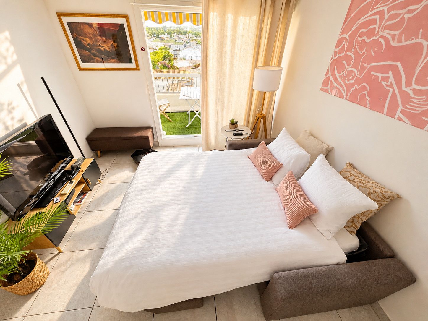 Een hotelkamer met een bed, een televisie, een bureau en een raam met uitzicht op een tuin.