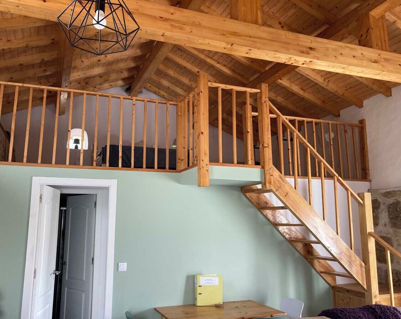 A wooden interior with a staircase leading to an upper level, a door, and a small table with a yellow object on it.