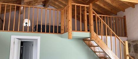 A wooden interior with a staircase leading to an upper level, a door, and a small table with a yellow object on it.