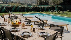Ein Essbereich im Freien mit Pool, Stühlen und Tisch, gedeckt für eine Mahlzeit.