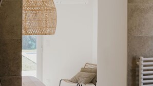 Ein Zimmer mit einem Bett, einer Korbschwinglichtleuchte, einem Sessel und einer Heizung.