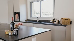 Eine moderne Küche mit schwarzem Arbeitsplatz, einem Einbauofen, einem Fenster und einem Korb auf der Arbeitsfläche.