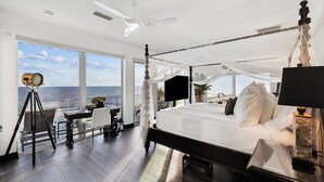 Ein geräumiges Schlafzimmer mit einem großen Bett, einem Deckenventilator und Meerblick.