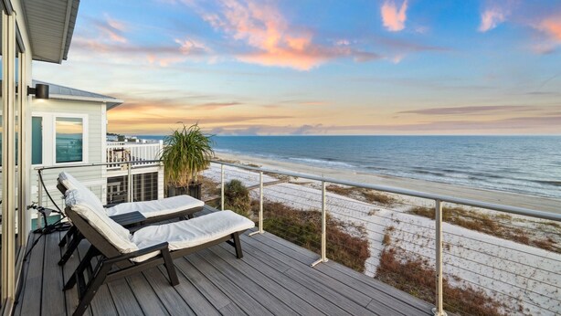 Ein Balkon mit zwei Liegestühlen mit Blick auf einen Strand.