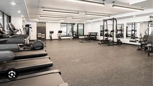 A modern gym with treadmills, weight machines, and a mirrored wall. - 1 bedroom with access to living & kitchen in adorable East Orange with AC & gym. (East Orange)