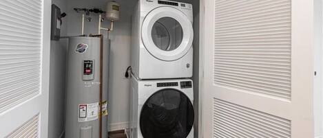 A compact laundry room with a water heater and two stacked washers.