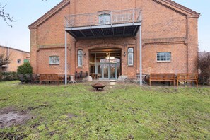 Een bakstenen gebouw met een balkon, een ruime entree en terrasplekken.