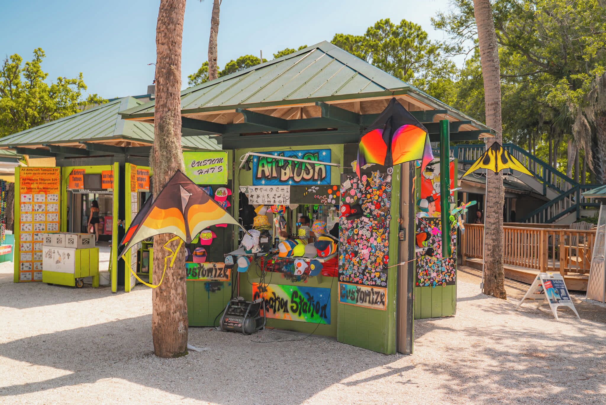 A colorful kiosk with a green roof, surrounded by trees.