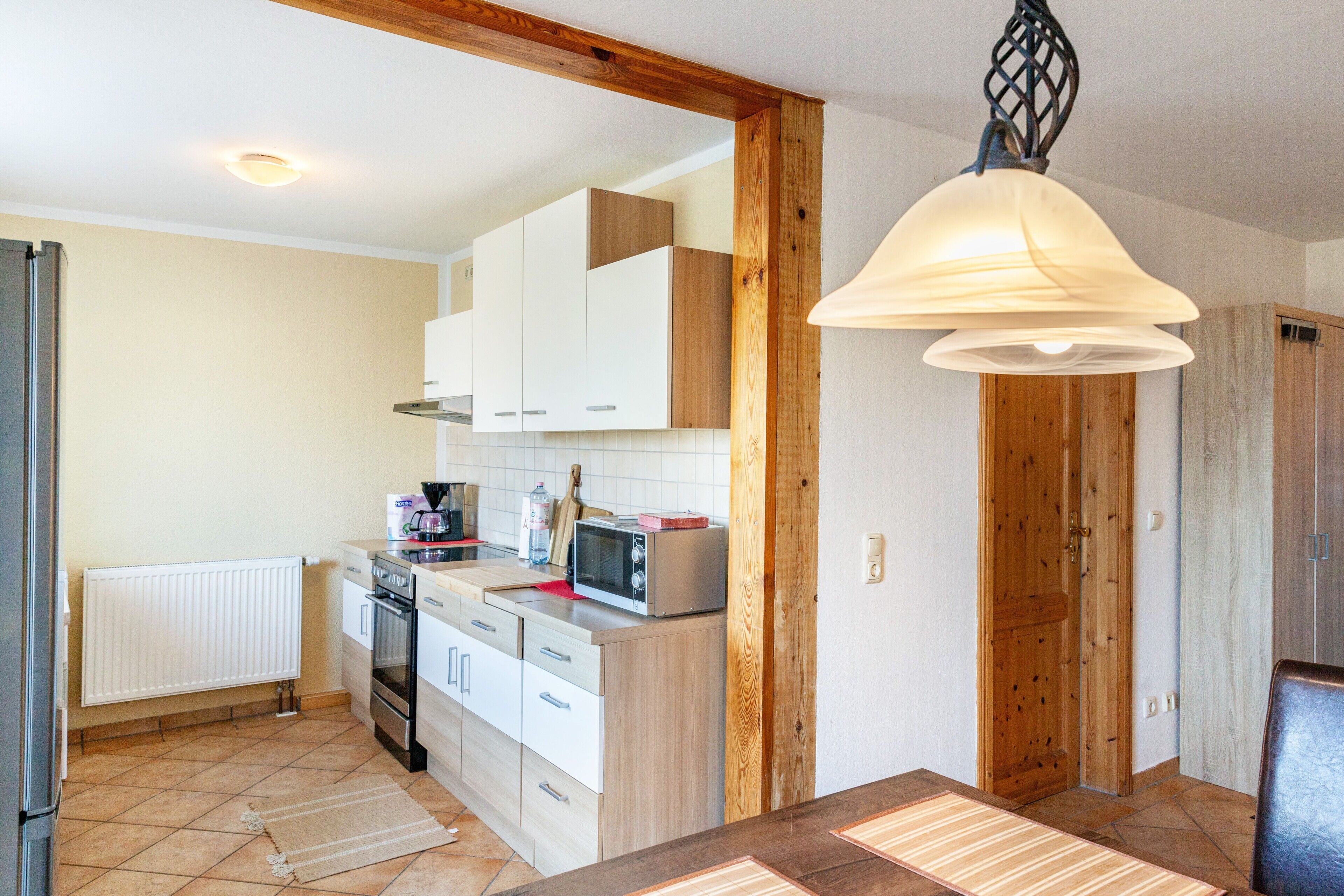 A kitchen with white cabinets, a microwave, and a wooden door.