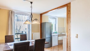 A dining area with a table, chairs, and a hanging light fixture.