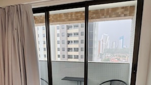 A hotel room with a large sliding glass door leading to an outdoor balcony with a view of surrounding buildings. - Flat Aconchegante em João Pessoa (João Pessoa)