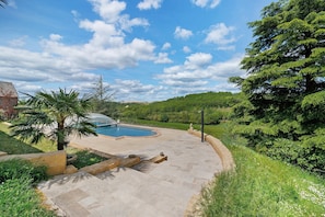 Un espace extérieur aménagé avec une piscine, un chemin de pierre et une végétation luxuriante.