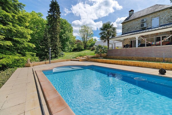 Ein Pool mit einem Steinhaus im Hintergrund.