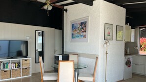 A modern living room with a glass dining table, white chairs, a TV, a bookshelf, and a fireplace. - Vacation bungalow with a wonderful view of Lake Garda and Monte Baldo (Tignale)