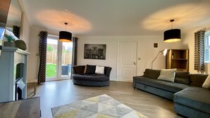 A spacious living room with a fireplace, two sofas, a patterned rug, and a large window with curtains. - Bracknell / Wokingham Charming Three Bedroom House (Bracknell)