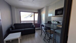 A compact living space with a sofa, a small dining table, and a kitchenette. - Mountain apartment Les Ménuires (Les Belleville)