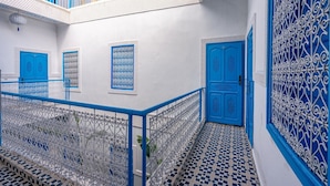 A courtyard with white walls and blue doors and windows, featuring intricate metal railings and a tiled floor. - Riad Les Secrets De Marrakech (Marrakech)