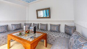 A cozy living room with patterned cushions, a wooden coffee table, and a decorative mirror. - Riad Les Secrets De Marrakech (Marrakech)