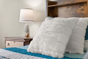 A bed with a blue and white quilt, a white fluffy pillow, a bedside lamp, and a wooden headboard. - 655 - Spacious 5-Bed Home with Private West-Facing Pool in Gated Community Near Orlando Attractions (Davenport)