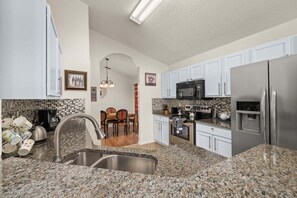 A kitchen with granite countertops, stainless steel appliances, and white cabinetry. - 655 - Spacious 5-Bed Home with Private West-Facing Pool in Gated Community Near Orlando Attractions (Davenport)