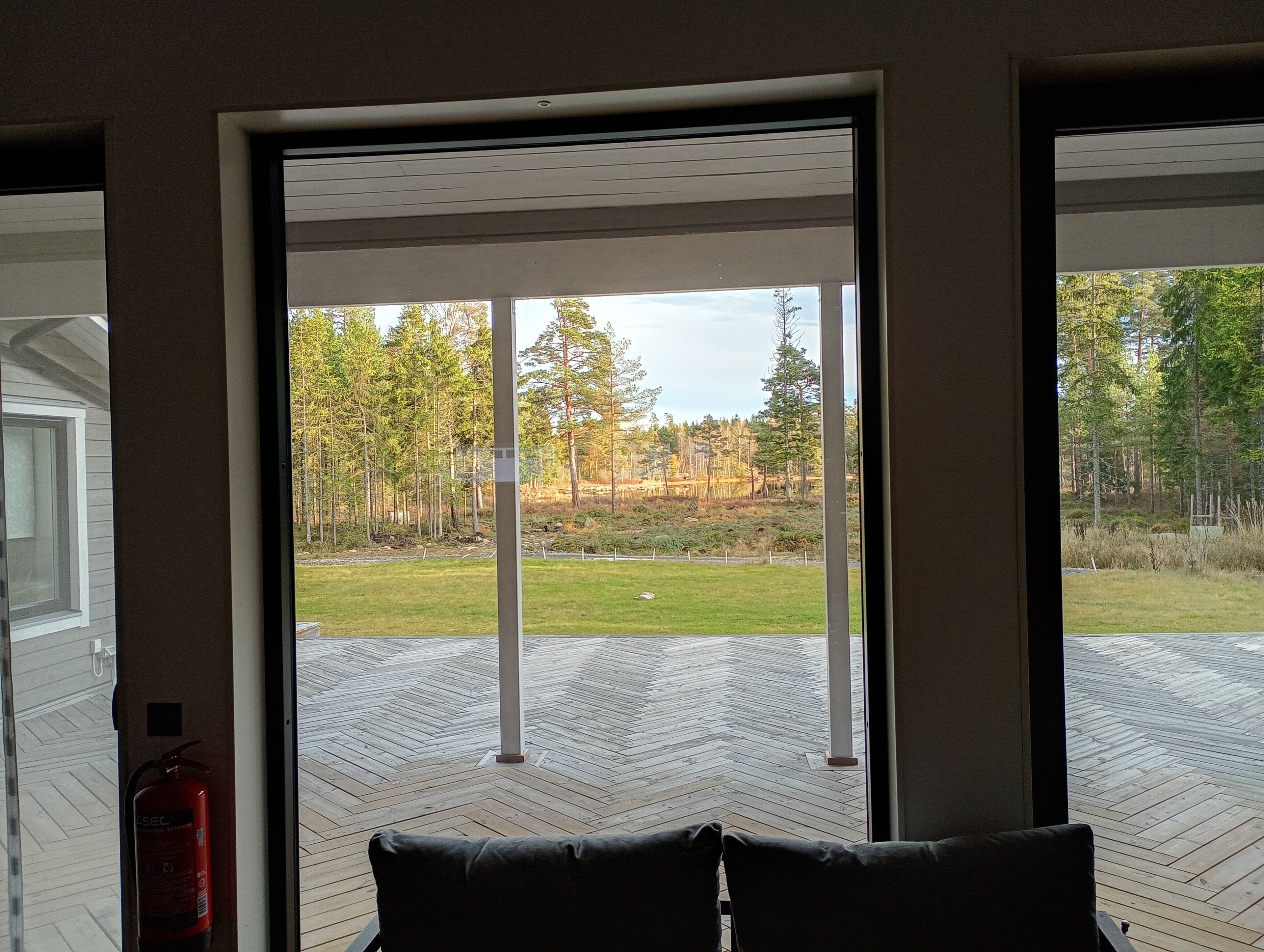 Ein Zimmer mit einer großen Schiebeglasdoor, die auf eine Terrasse mit einem Fischgrätenbodenparkett führt.