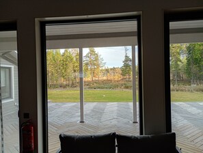 Una habitación con un gran ventanal corredero que da a una terraza exterior con piso de diseño en espiga.