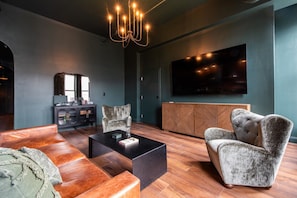 A modern living room with a large flat-screen TV, a wooden coffee table, and a sofa. - Hollyhock Suite 402: 4 bed/2 bath with soaking tub (Louisville)