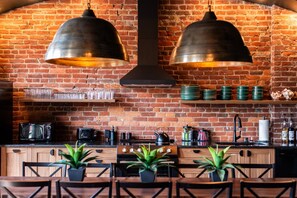 A kitchen with a brick wall, two hanging pendant lights, a microwave, a toaster, a kettle, and a sink. - Hollyhock Suite 402: 4 bed/2 bath with soaking tub (Louisville)