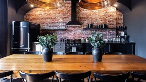 Una cucina moderna con pareti in mattoni a vista, un tavolo da pranzo in legno e due piante in vaso.