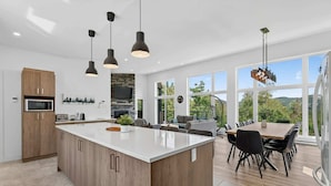 Une cuisine moderne dotée d’un grand îlot central, de meubles en bois et de luminaires suspendus.