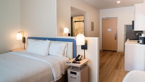 A hotel room with a bed, bedside lamps, a desk with a phone, and a door leading to a bathroom. - Homewood Suites By Hilton Corpus Christi Downtown (Corpus Christi)
