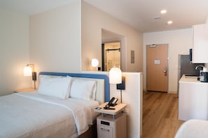 A hotel room with a bed, bedside lamps, a desk with a phone, and a door leading to a bathroom. - Homewood Suites By Hilton Corpus Christi Downtown (Corpus Christi)