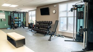 A gym with weightlifting equipment, a bench, and a wall-mounted clock. - Homewood Suites By Hilton Corpus Christi Downtown (Corpus Christi)