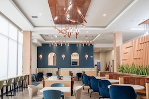 A modern hotel lobby with a seating area, a reception desk, and a wall with vertical wooden slats. - Homewood Suites By Hilton Corpus Christi Downtown (Corpus Christi)