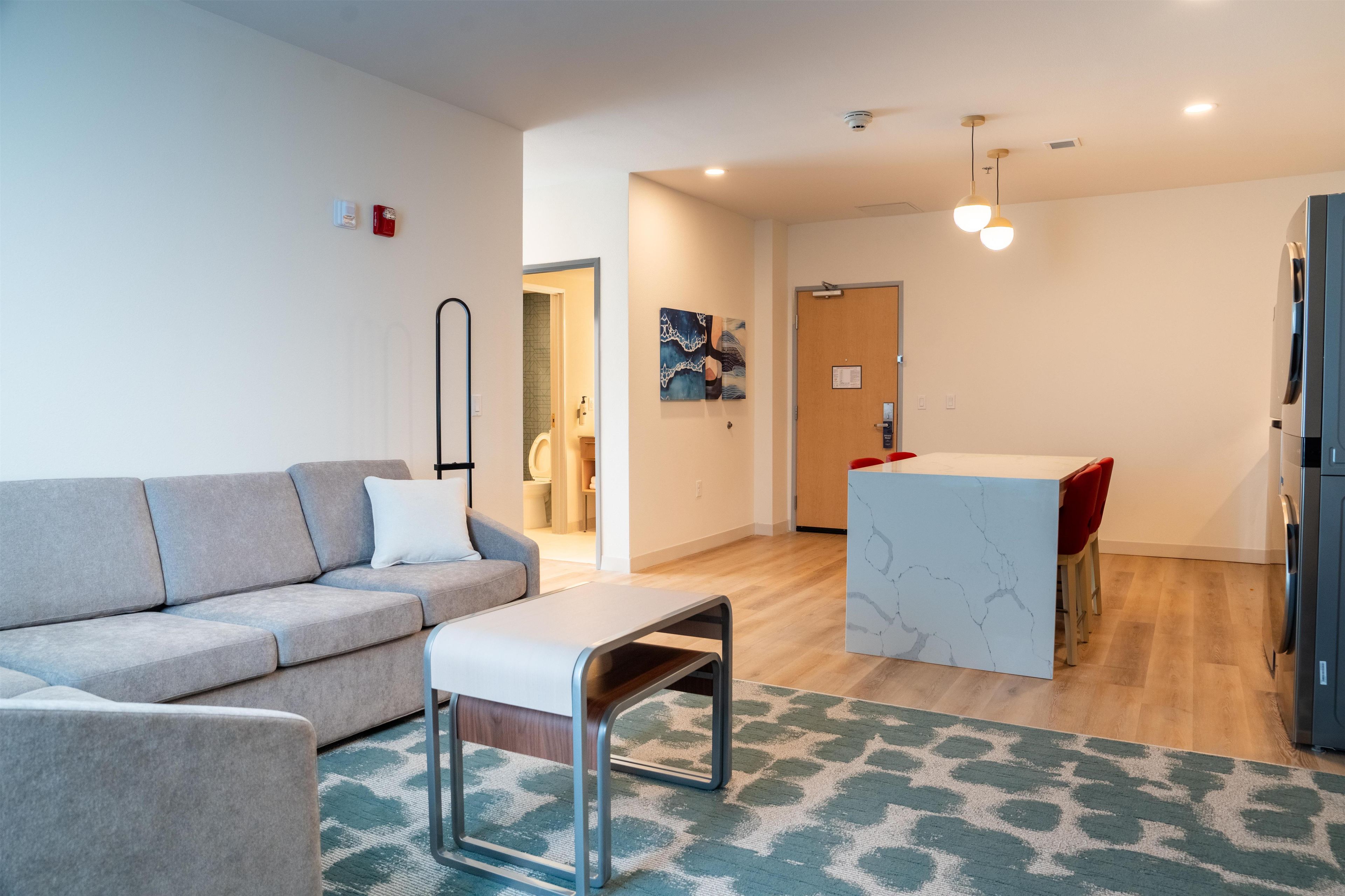A modern living room with a grey sofa, a small table, and a patterned rug.