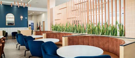 A modern hotel lobby with seating areas, a reception desk, and a decorative wall with vertical elements.