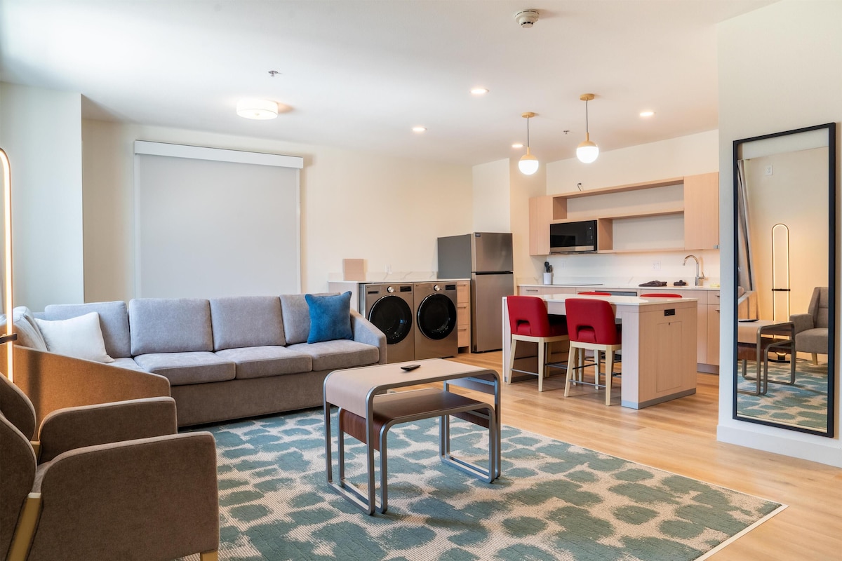 A modern apartment with a living room, kitchenette, and a dining area.