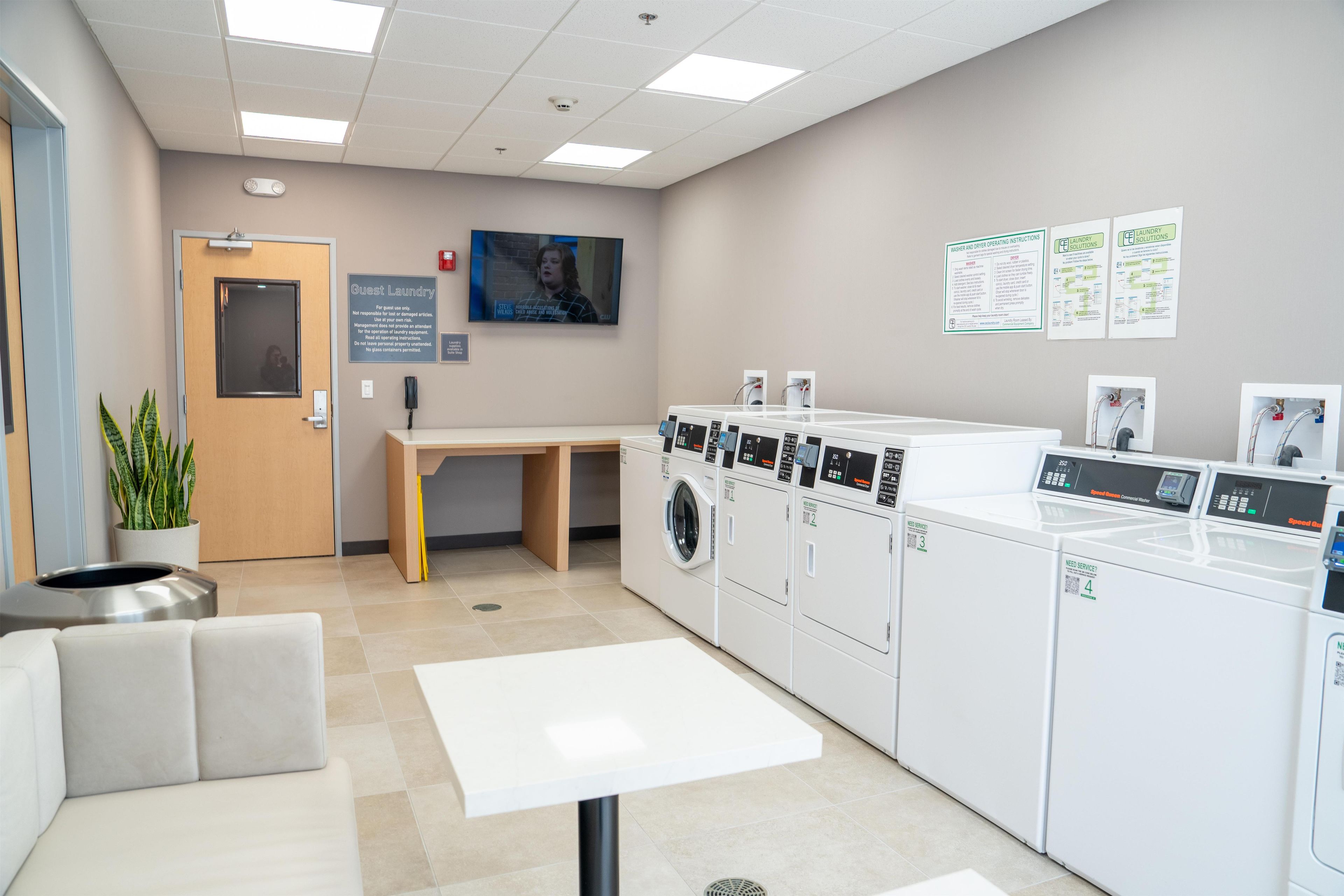 A guest laundry area with a table, chairs, and multiple washing machines.