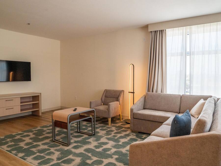 Una sala de estar moderna con sofá, sillón y televisor en la pared.