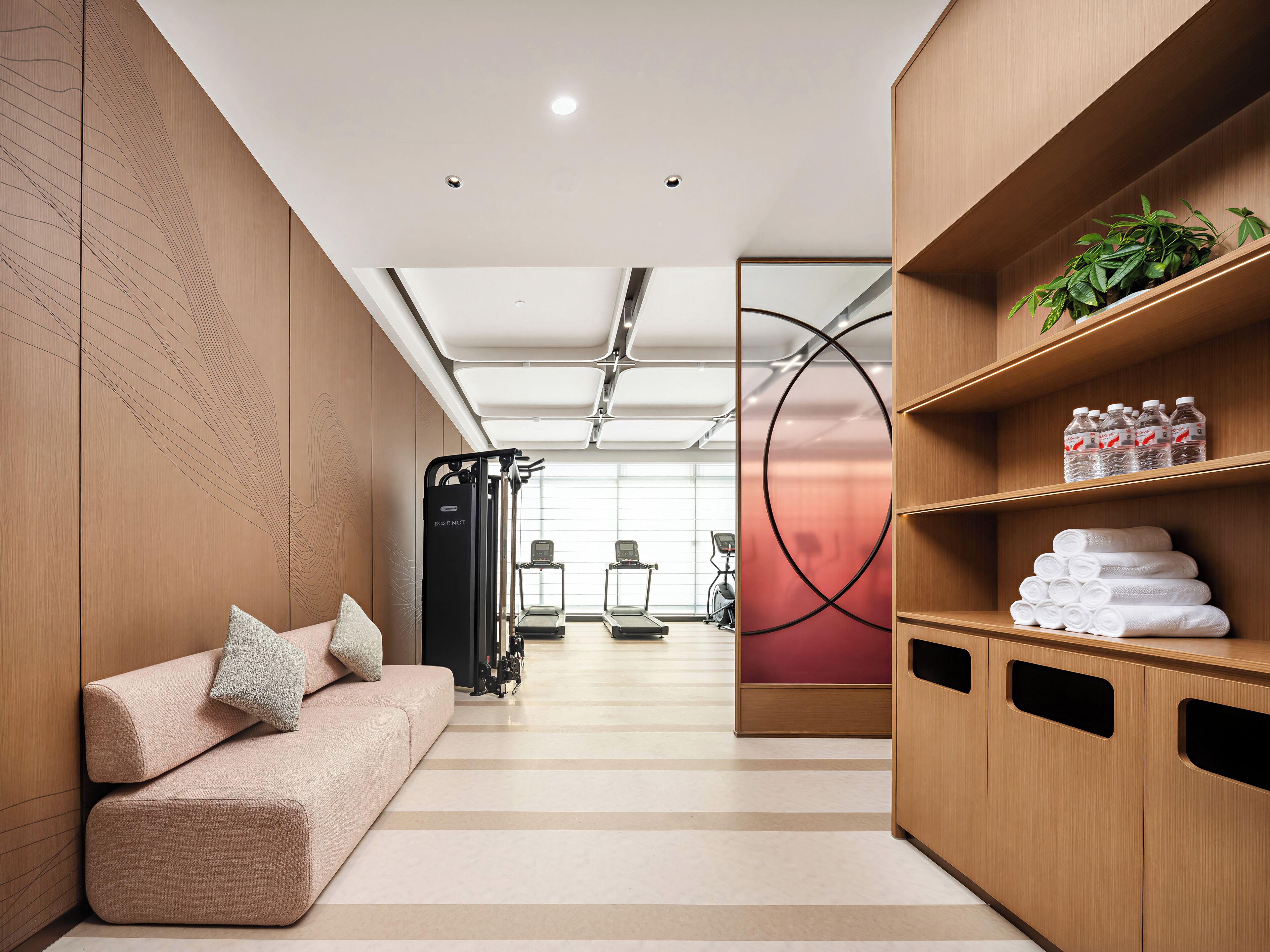 Ein modernes Fitnessstudio mit Trainingsgeräten, einer Sitzecke und einer Wasserspenderstation.
