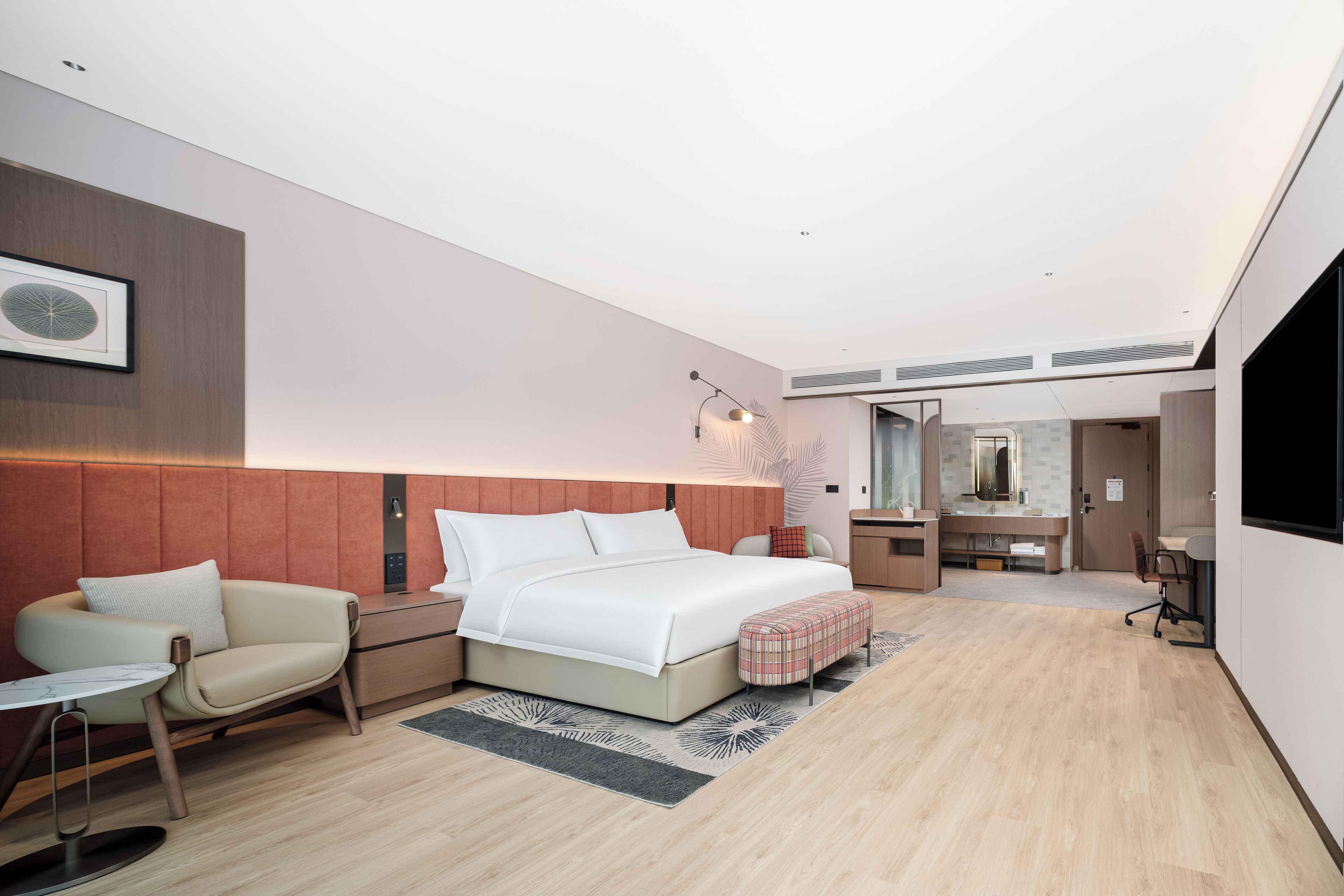Une chambre d’hôtel moderne équipée d’un lit, d’un bureau, d’une chaise, d’une petite table et d’un miroir.