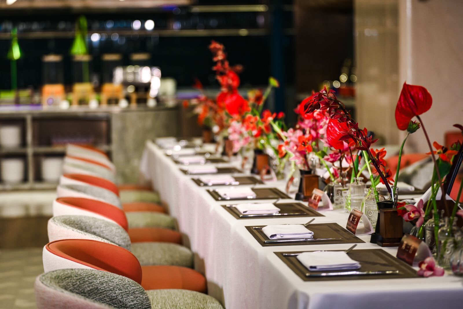 A long dining table with multiple place settings, each with a menu, a napkin, and a glass.