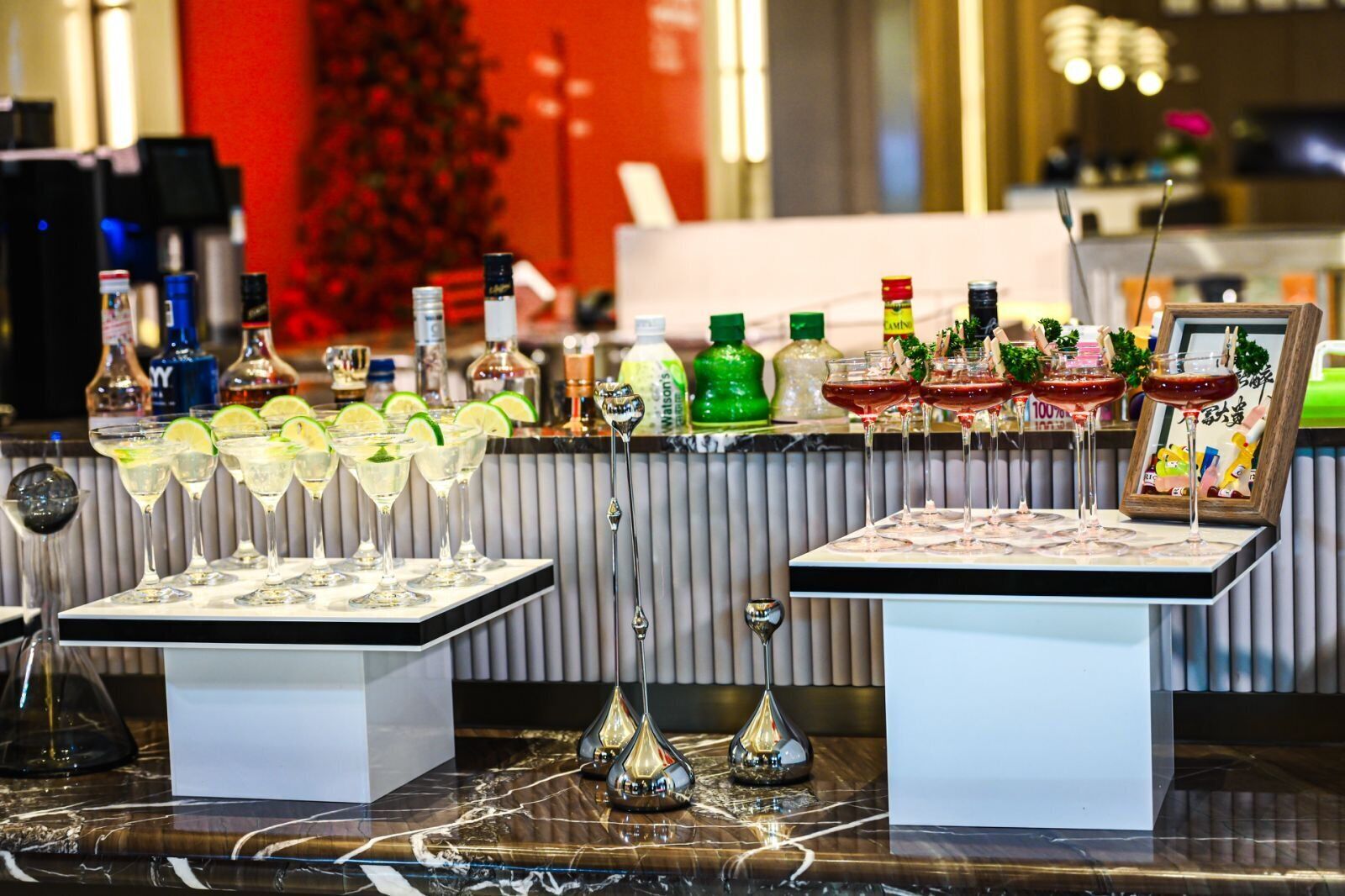 A bar area with multiple glasses of drinks, bottles of liquor, and decorative items.