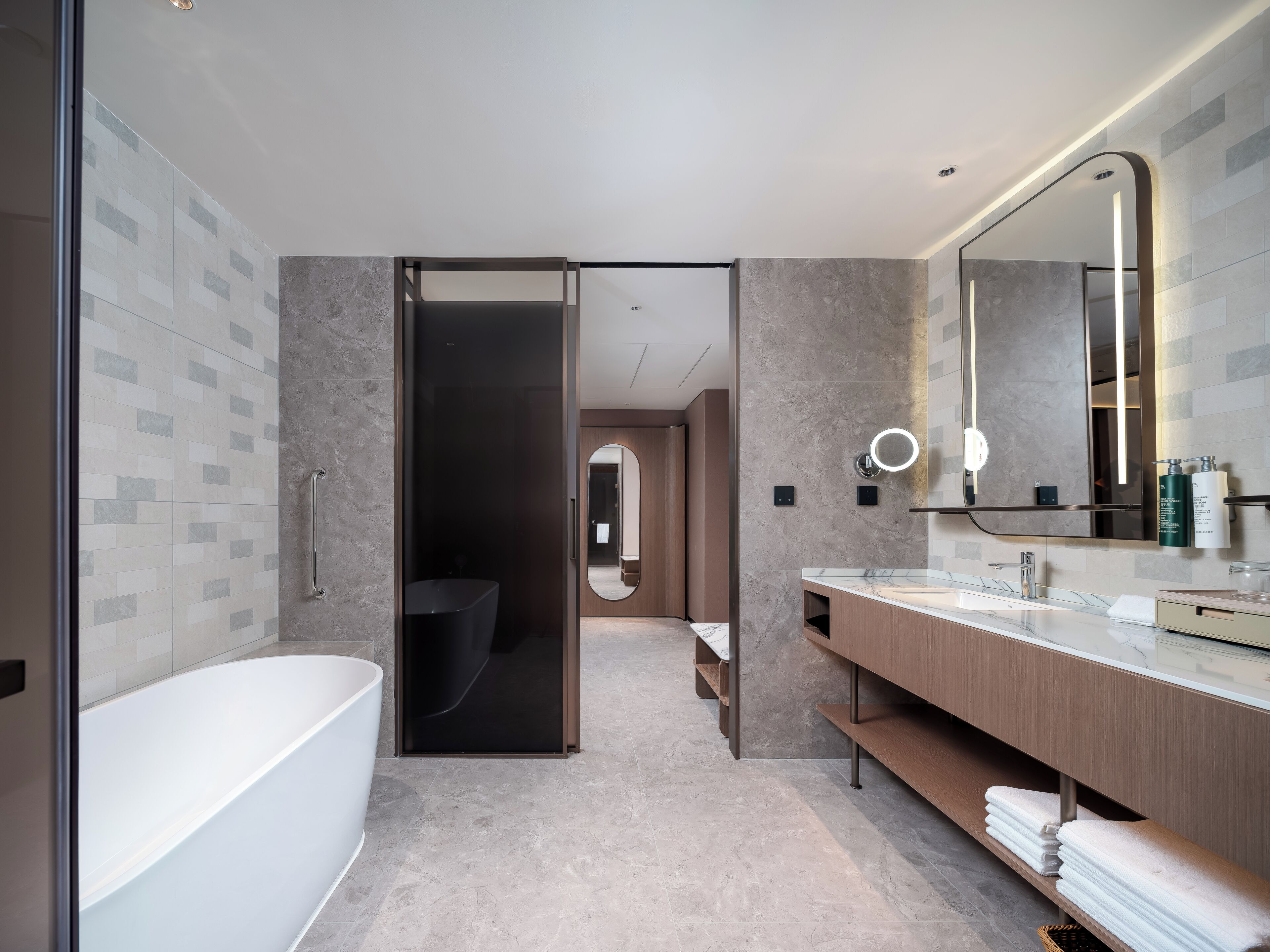 A modern bathroom with a bathtub, a vanity with a mirror, and a shower area.