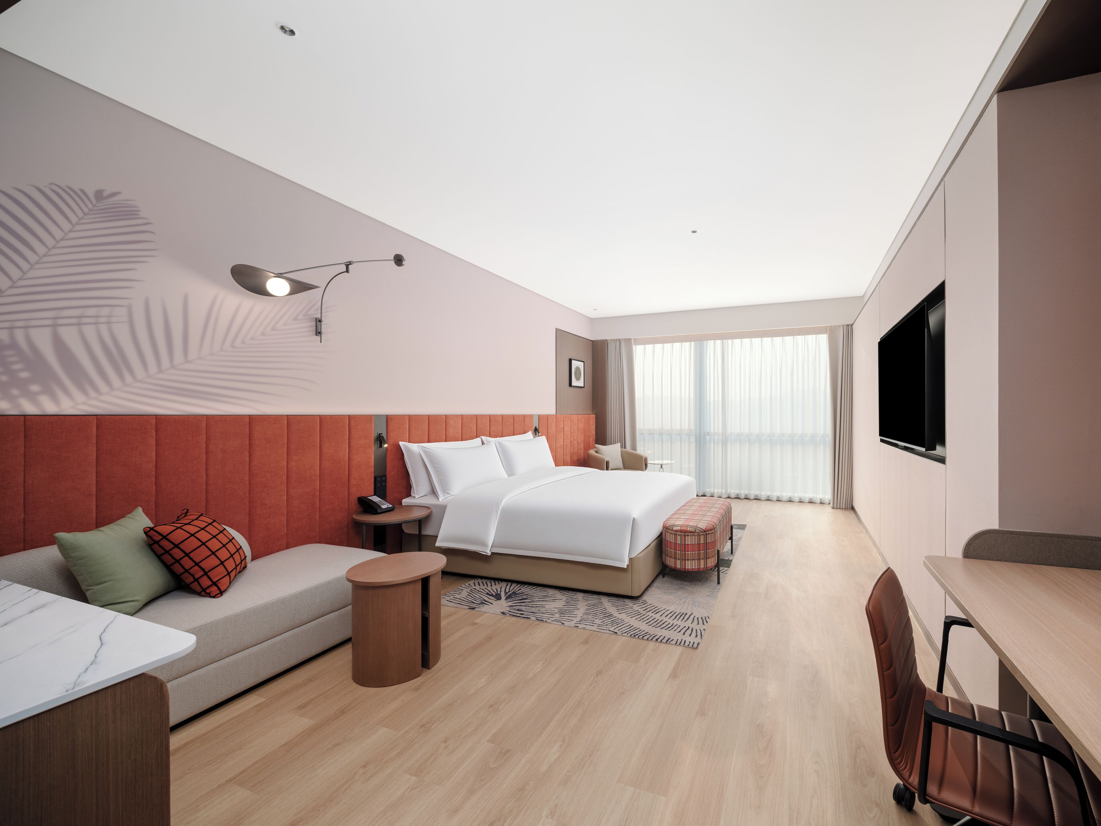 Una habitación de hotel moderna con cama, sofá, escritorio y televisor.
